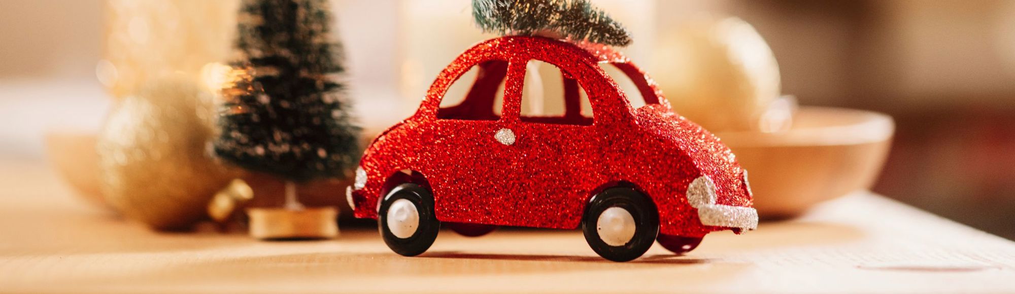 Een rood speelgoed glitter autootje met een kerstboom op het dak